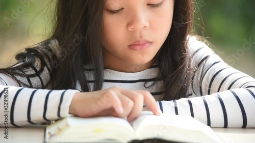 cute little asian girl in reading bible. hands holding on a holy bible. little child girl hands folded in prayer on a holy Bible for faith,spirituality and religion concept.