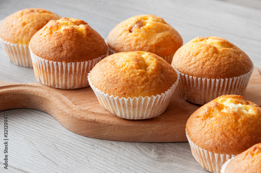 Fresh homemade delicious muffins are taken out of the oven and they cool on the kitchen table. Sweet dessert. Fresh homemade delicious muffins are taken out of the oven and they cool on the kitchen table. Sweet dessert.