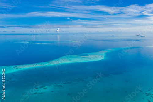 Tropical islands and atolls in Maldives from aerial view. Famous travel destination and luxury vacation or summer holiday concept. Aerial landscape of blue sea and resorts, hotels. Beautiful nature