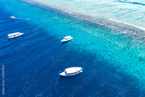 Beautiful turquoise ocean water with boats on it top view aerial photo. Maldives island and sea, amazing aerial photo. Wonderful landscape scenery, exotic travel landscape, summer vacation, holiday © icemanphotos
