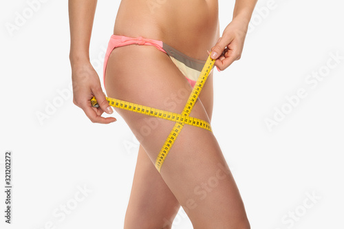 a woman with a perfect figure uses a measuring tape to measure her dimensions