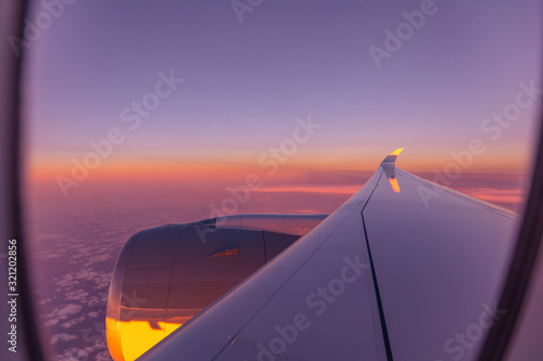 Sunset sky from the airplane window. View on the sunset and airplane wing from the inside