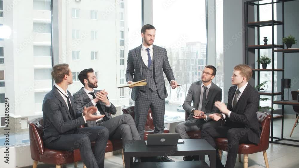 Positive business team consisted of young leaders men sit on leather chair and laugh, gathered to talk about business. Men have free time after meeting. big panoramic window in the background Positive business team consisted of young leaders men sit on leather chair and laugh, gathered to talk about business. Men have free time after meeting. big panoramic window in the background