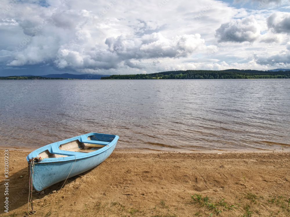 View to anchored laminate blue rowing boat at large lake