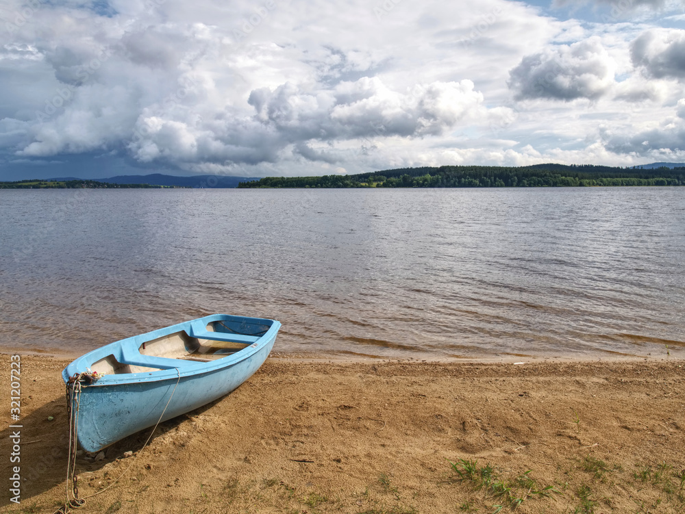 View to anchored laminate blue rowing boat at large lake View to anchored laminate blue rowing boat at large lake