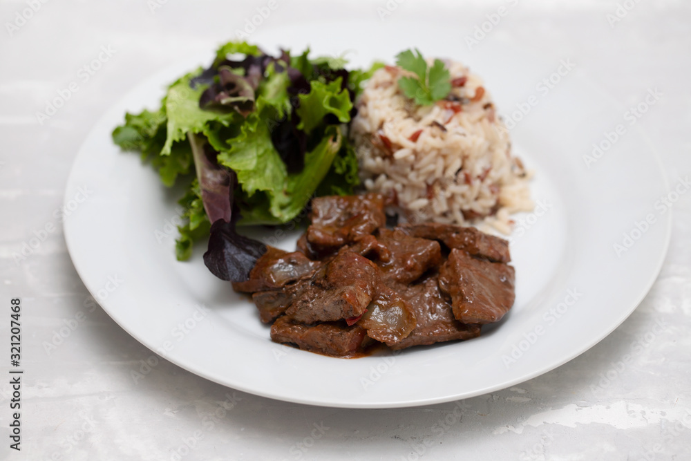 fried liver with salad and boiled rice on white plate