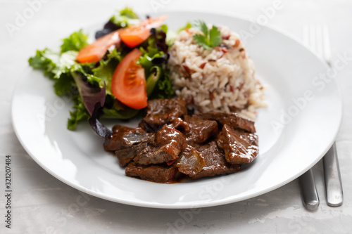 fried liver with salad and boiled rice on white plate