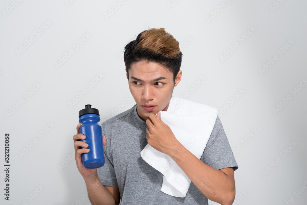 Φωτογραφία young Asian fitness man holding towel and bottle with water isolated on a white