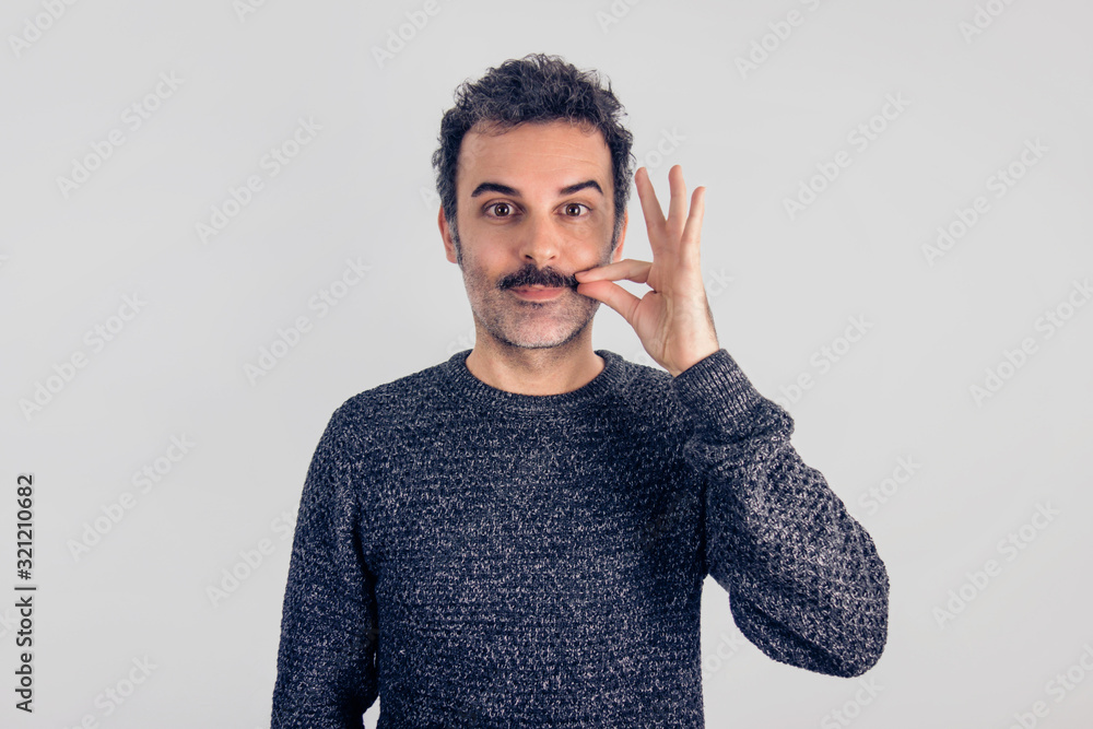 Φωτογραφία Funny portrait of brown, smiling, handsome man touching his mustache with gray sweater