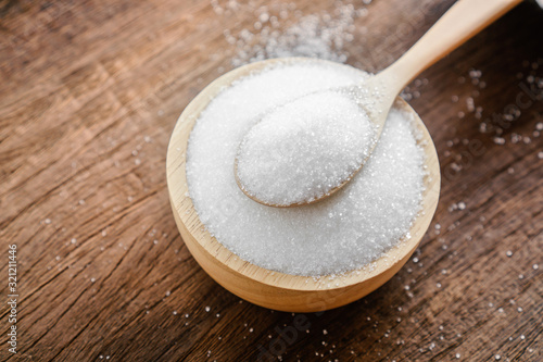 sugar in bowl with spoon on wooden table closeup 