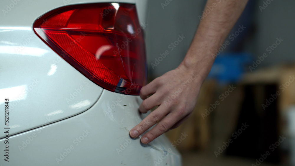 Mechanic examines damage and touches a car Mechanic examines damage and touches a car