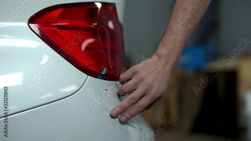 Mechanic examines damage and touches a car  © iaginzburg
