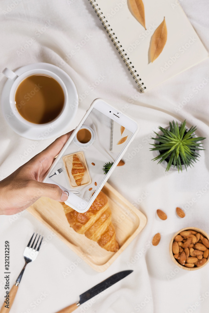 Φωτογραφία Coffee, croissant , plant, almond and notebook on a white desk was flat