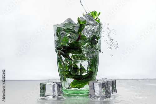 ice and mint fall in a cocktail spray. Rum with mint and ice in a glass.