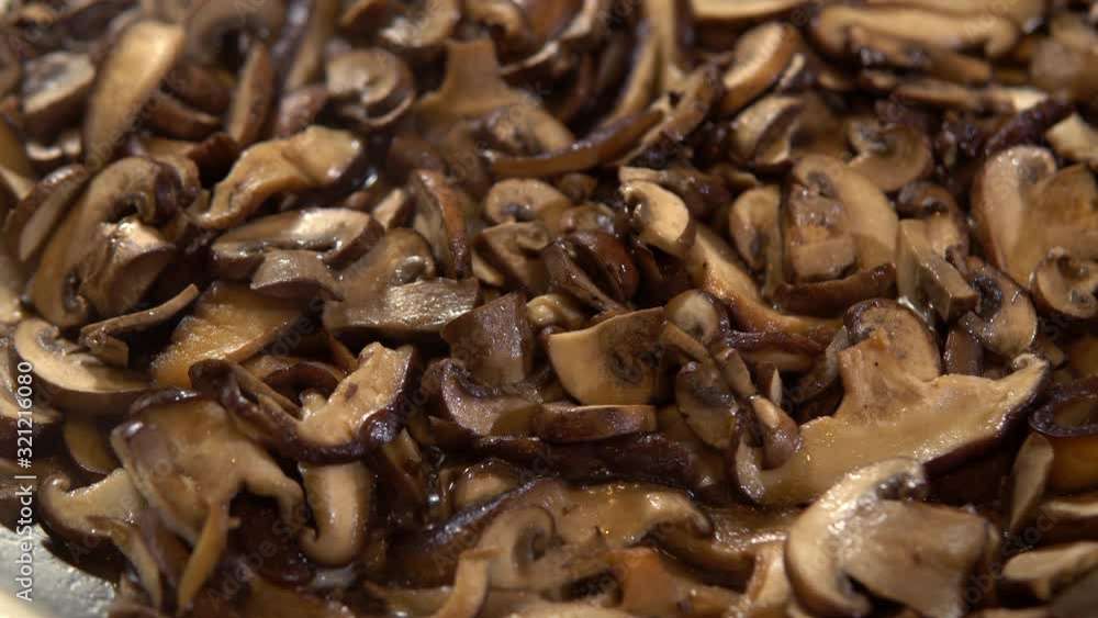 Cooking chopped button mushroom slices in hot frying pan, close up Cooking chopped button mushroom slices in hot frying pan, close up