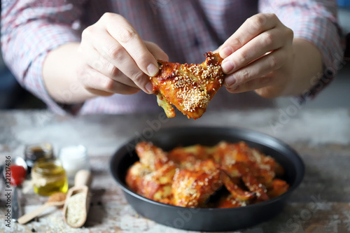 Selective focus. A man eats chicken wings with his hands.