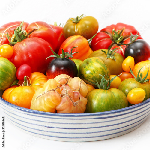 Bunte  exotische   historische Tomaten Vielfalt  von schwarz bis gestreift  s     und saftig in einer Schale vor wei  em Hintergrund presentiert.