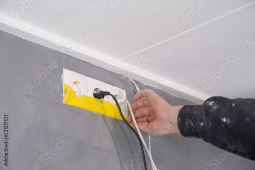 plasterer removes the yellow protective tape from the socket
