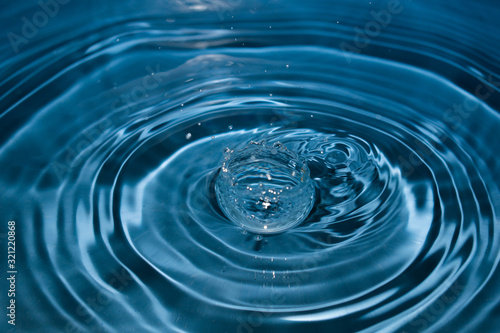 water drop splash in a glass blue colored. Fresh liquid concept. Close up.