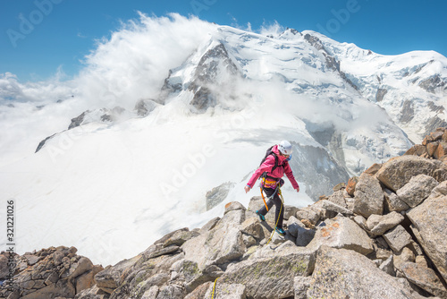 Female Mountain Climber hiking high up in the mountains with Mont Blanc Massif behind her 