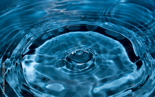 water drop splash in a glass blue colored. Fresh liquid concept. Close up.