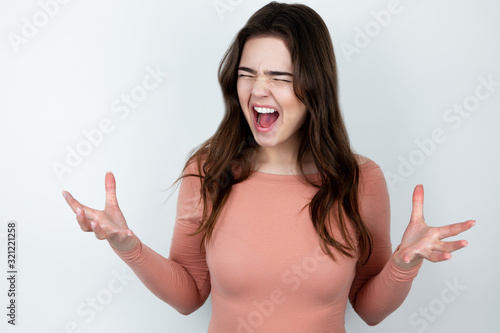 young beautiful brunette woman standing on isolated white background looking angry ,splash of emotions