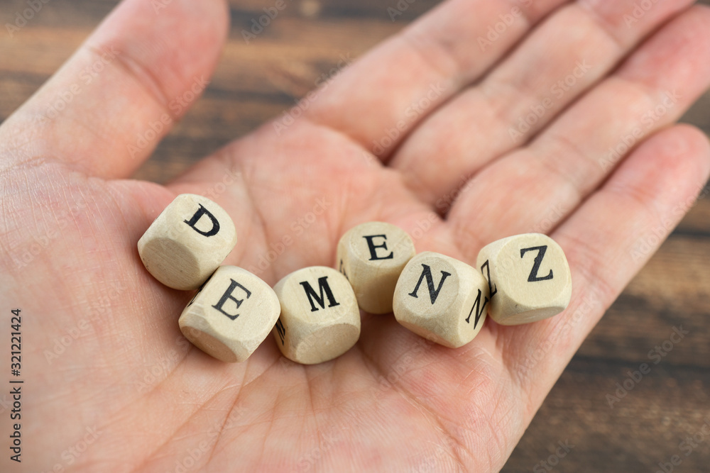 Hand with wood cubes and the German word for dementia, wooden background Hand with wood cubes and the German word for dementia, wooden background