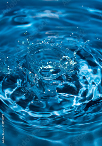 water drop splash in a glass blue colored. Fresh liquid concept. Close up.