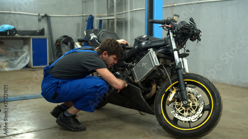 Mechanic examines a motorcycle in auto repair shop