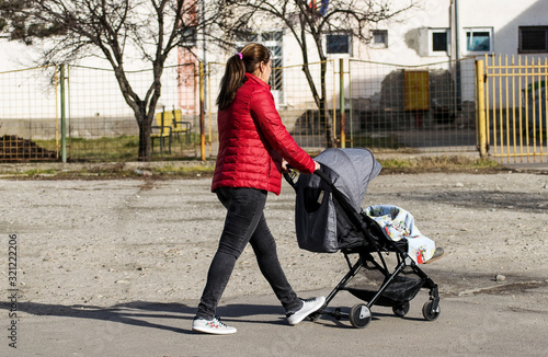Young mother with baby stroller on the street.
