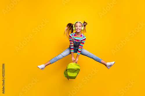 Full length photo energetic crazy schoolkid hold backpack bags enjoy school lessons listen songs wear denim jeans striped sweater footwear isolated bright shine yellow color background