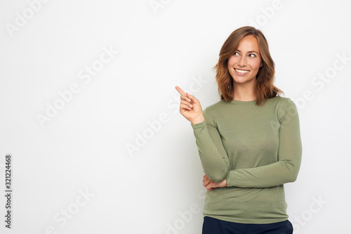 young woman pointing at your product and looks at it.