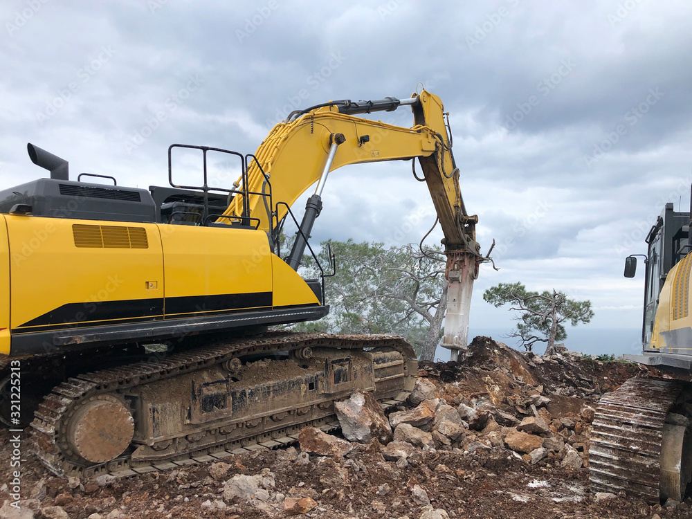 Obraz premium Excavator and hydrohammer during road construction on the rocky soils