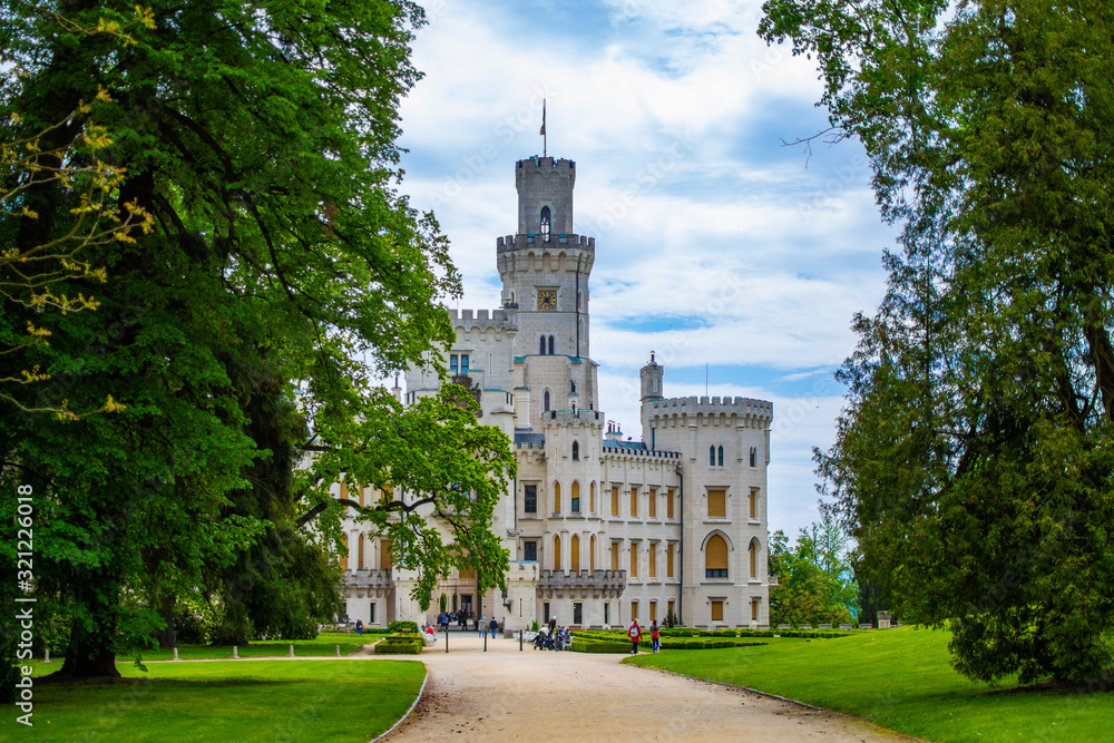 Facade of Hluboka Castle (Hluboka nad Vltavou Castle), also called The State Chateau of Hluboka, between trees from Zamecky Park, in South Bohemia region, Czech Republic