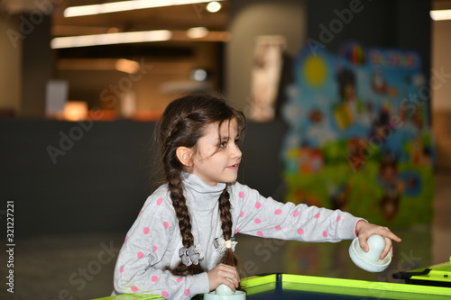 beautiful little girl plays children's games in a children’s play area