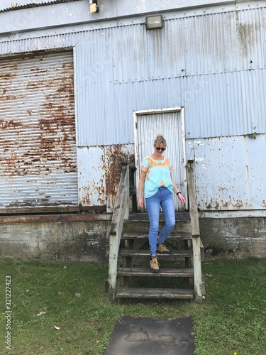 Frau auf Stufen vor altem Fabrikgebäude mit Wellblech und Tür © Andrea