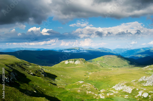 a beautiful mountain scenery. A dramatic  blue sky with many clouds. The heights of the mountains covered with green grass and many trees  on July. Photo taken somewhere in Romania  Europe.