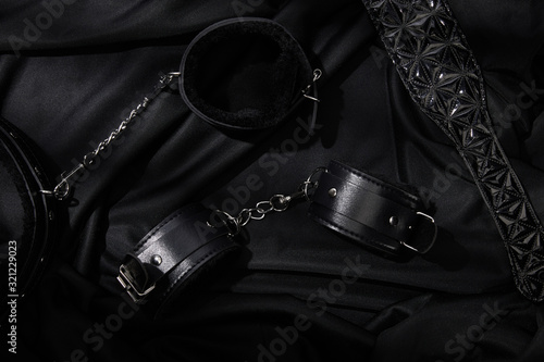 top view of handcuffs and paddle on black textile background