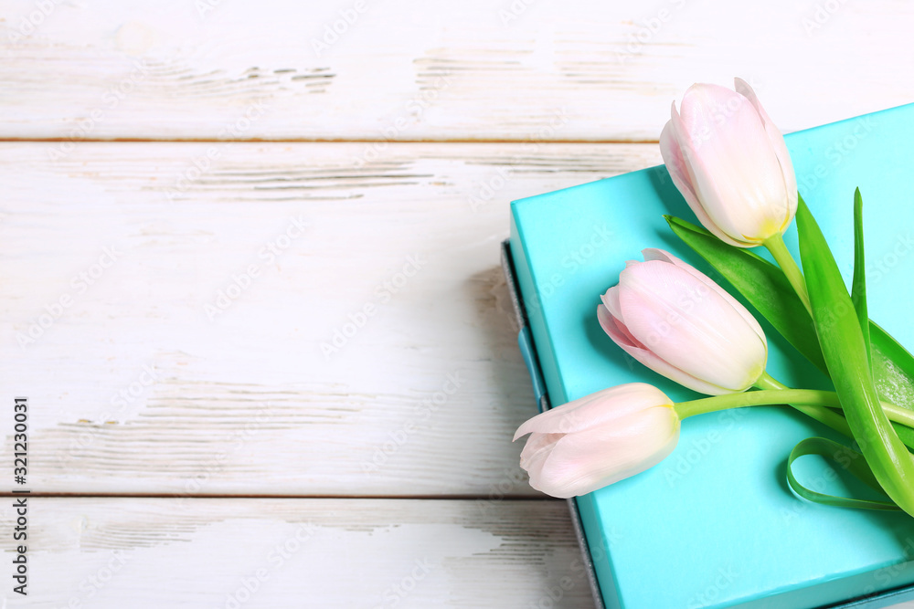 Pink tulips on a turquoise box. Against the background of the boards. Close-up. Top view. Pink tulips on a turquoise box. Against the background of the boards. Close-up. Top view.