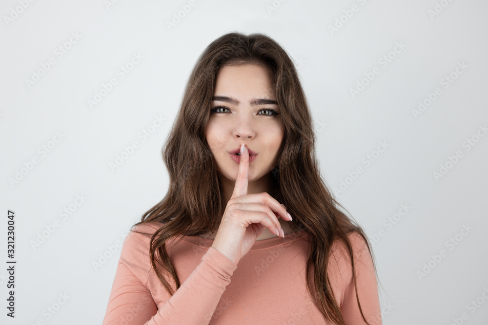 young beautiful brunette woman holding her finger near her lips showing quiet sign standing on isolated white background young beautiful brunette woman holding her finger near her lips showing quiet sign standing on isolated white background