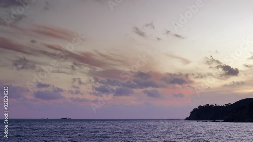 Dark island surrounded foamy waves under cloudy sky photo