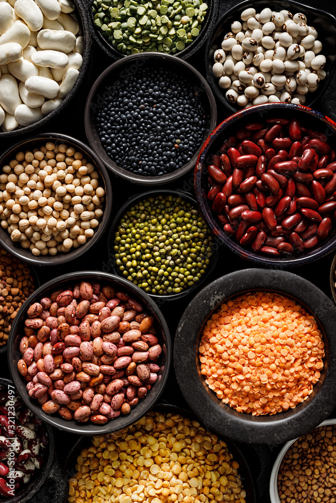Legumes, a set consisting of different types of beans, lentils and peas on a black background, top view, close up. The concept of healthy and nutritious food
