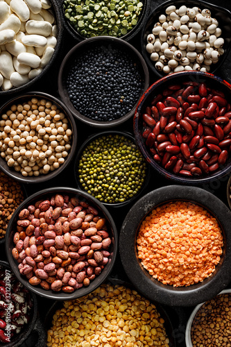 Legumes, a set consisting of different types of beans, lentils and peas on a black background, top view, close up. The concept of healthy and nutritious food