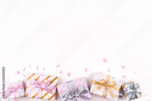 Set of gift boxes with bows and confetti on a white background. Flat lay composition. Birthday, christmas, wedding or another holiday concept.