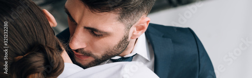 panoramic shot of businessman hugging and kissing secretary in office
