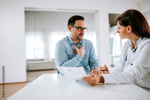 Fototapeta Handsome male patient talking to a female doctor, portrait.