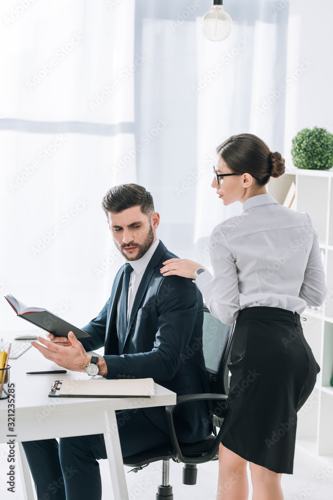 secretary touching shoulder of handsome businessman in office secretary touching shoulder of handsome businessman in office