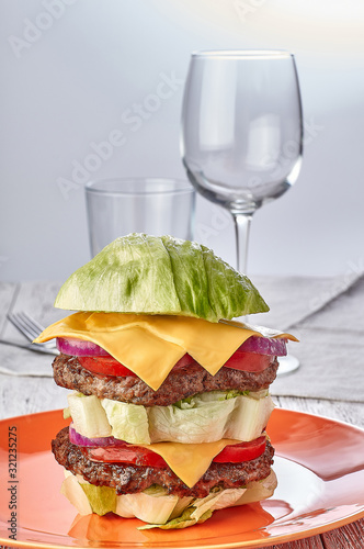 burger without bun on lettuce, gluten free, with vegetables, beef patties and cheese. on wooden background