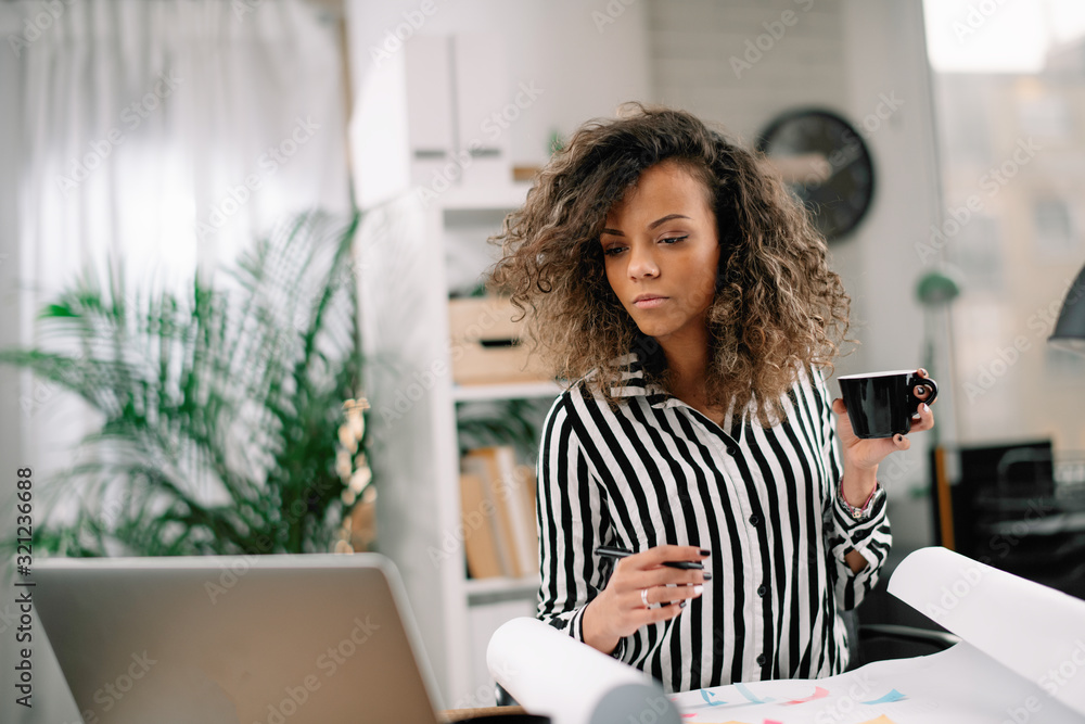 Beautiful african businesswoman in office. Woman at work drinking coffee while working. Beautiful african businesswoman in office. Woman at work drinking coffee while working.