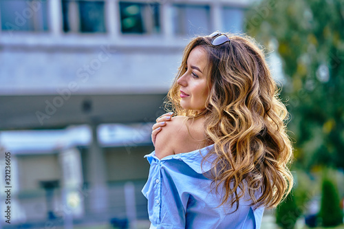 Portrait of a young beautiful pensive woman with brown long curly hair and brown eyes looking into the distance. Close-up. © afefelov68